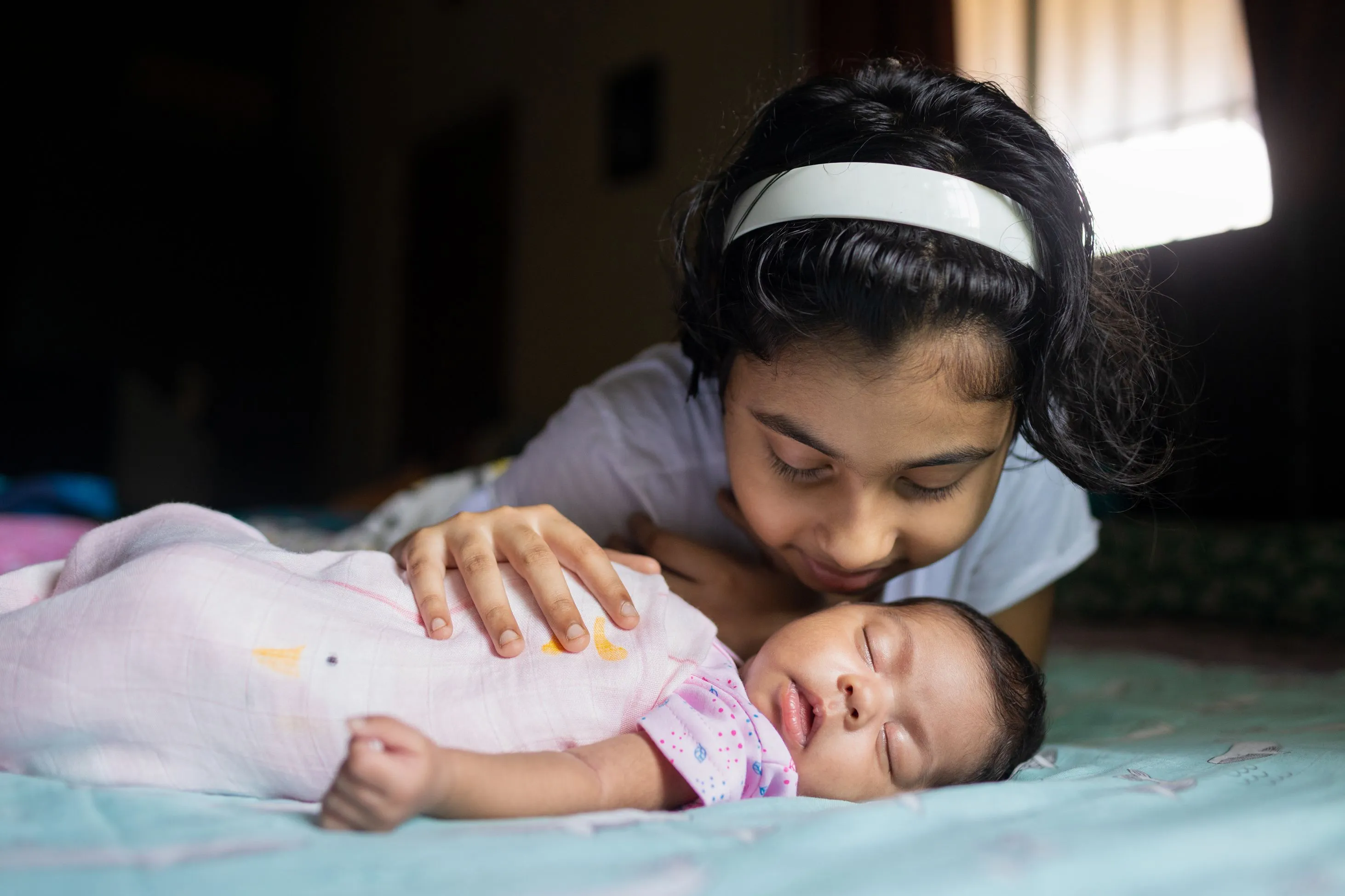Girl cuddling newborn baby sibling